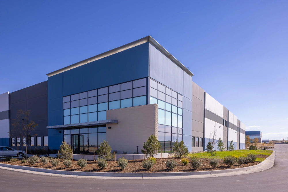an angled view of an industrial building showing the main corner entrance with a cantilever overhang above the door